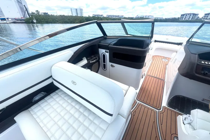 Slide: The Image of 2017 Cobalt R30 boat interior with white seating and wood flooring on a sunny day. - 17