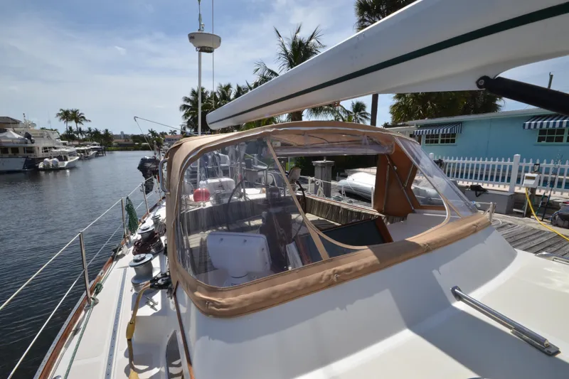 Slide: The Image of 1992 Hinckley Sou'wester 59 yacht docked, featuring a covered cockpit and scenic marina backdrop. - 15