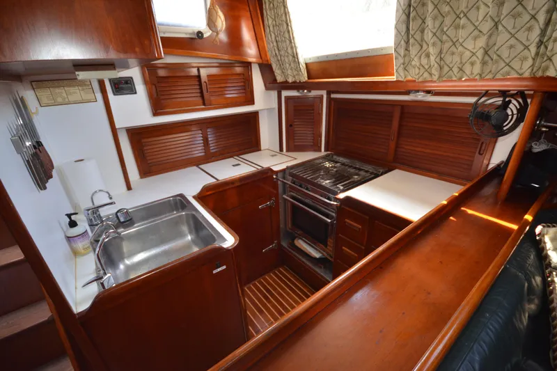 Slide: The Image of 1992 Hinckley Sou'wester 59 yacht kitchen with wooden cabinetry, stainless steel sink, and stove. - 25