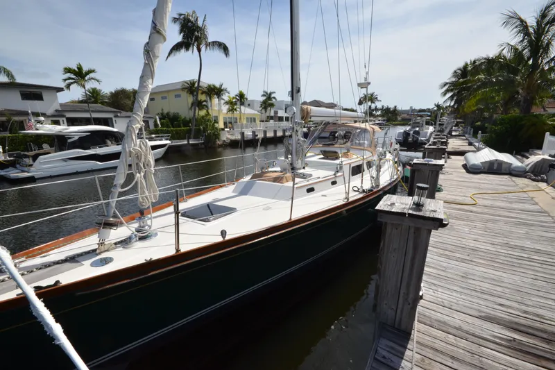 Slide: The Image of Sailboat Hinckley Sou'wester 59, 1992 model, docked by a wooden pier with palm trees. - 3