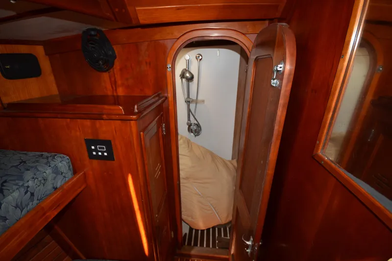 Slide: The Image of Interior of 1992 Hinckley Sou'wester 59 yacht, featuring wooden cabinetry and a compact shower area. - 34