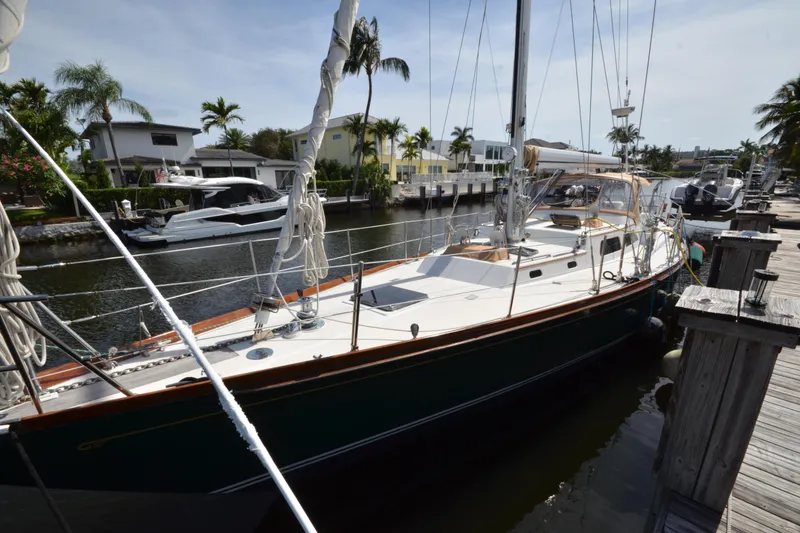 Slide: The Image of Hinckley Sou'wester 59 sailboat docked in a sunny marina, surrounded by palm trees. - 5