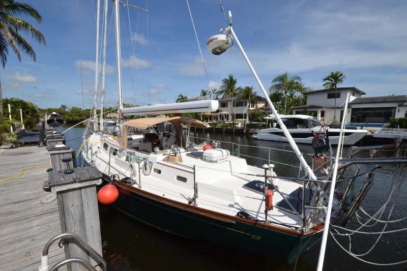 Slide: The Image of Hinckley Sou'wester 59 sailboat docked in a sunny marina, surrounded by palm trees. - 8