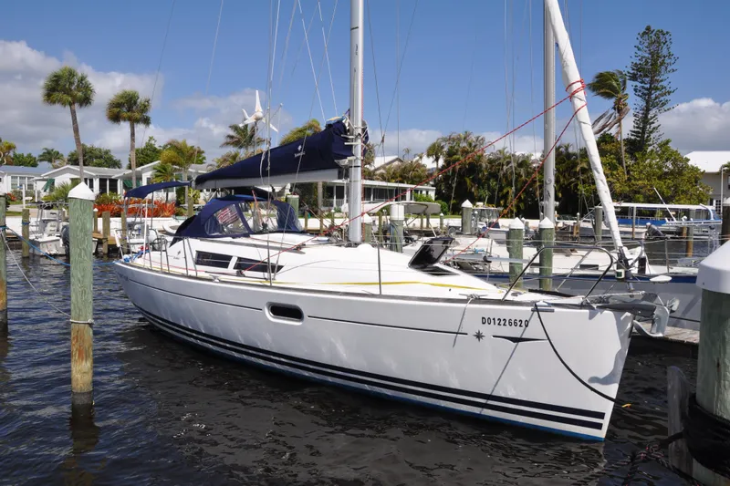The Image of 2010 Jeanneau Sun Odyssey 36i sailboat docked at a marina with palm trees. - 0