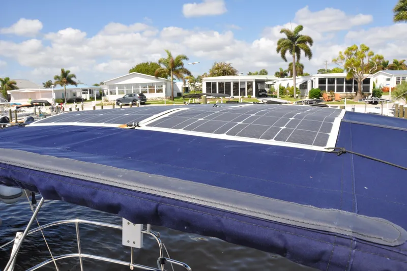 Slide: The Image of Jeanneau Sun Odyssey 36i sailboat with solar panels, docked near waterfront homes. - 12