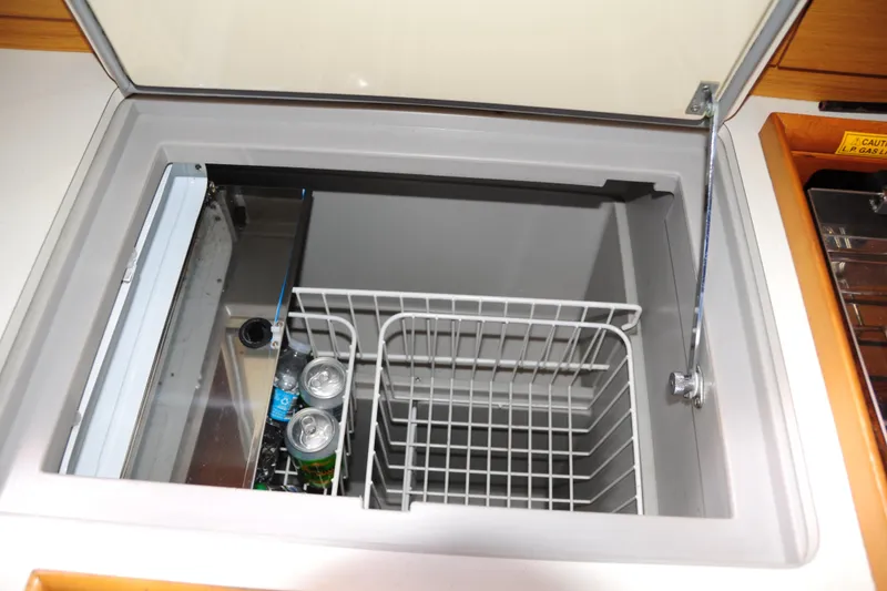 Slide: The Image of Open fridge compartment on Jeanneau Sun Odyssey 36i yacht, showing drinks and storage space. - 38