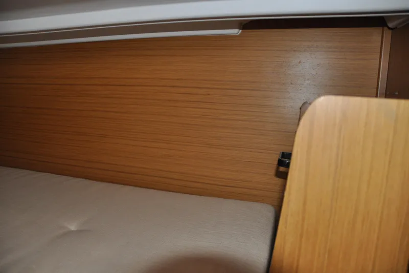 Slide: The Image of Interior cabin of 2010 Jeanneau Sun Odyssey 36i sailboat, featuring wooden paneling and a cushioned bed. - 59