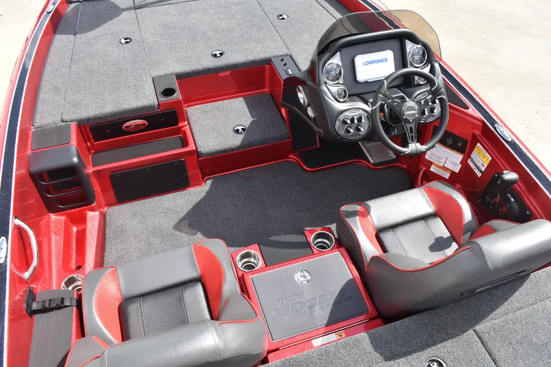 Slide: The Image of 2026 Triton 18 TrX bass boat in red on a trailer, parked outside a warehouse. - 17