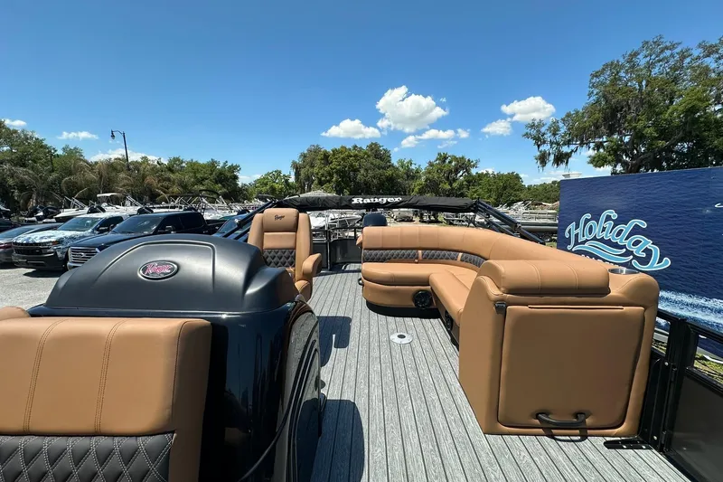 Slide: The Image of 2026 Ranger Reata 220FC boat with tan seating, parked outdoors under a clear blue sky. - 13