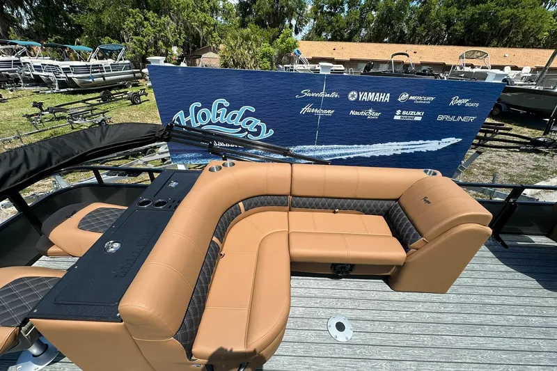 Slide: The Image of 2026 Ranger Reata 220FC boat with tan seating, displayed outdoors at a dealership. - 18