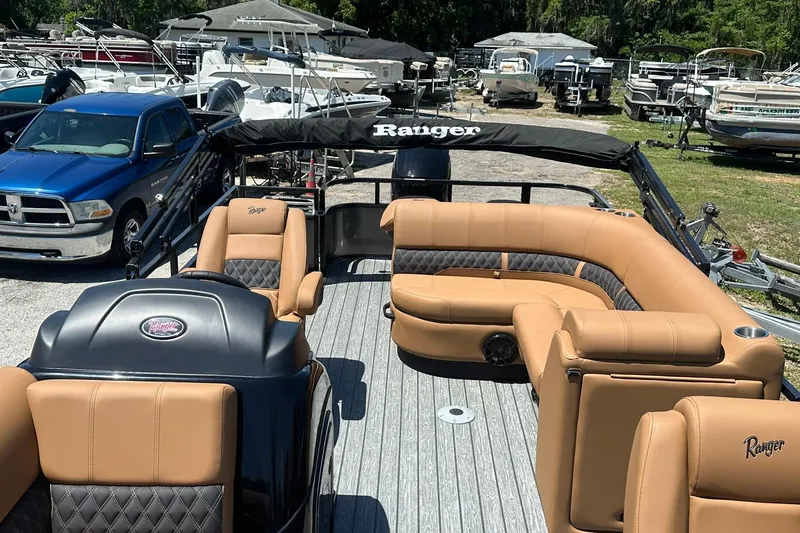 Slide: The Image of 2026 Ranger Reata 220FC pontoon boat with tan seating, parked in a marina. - 8
