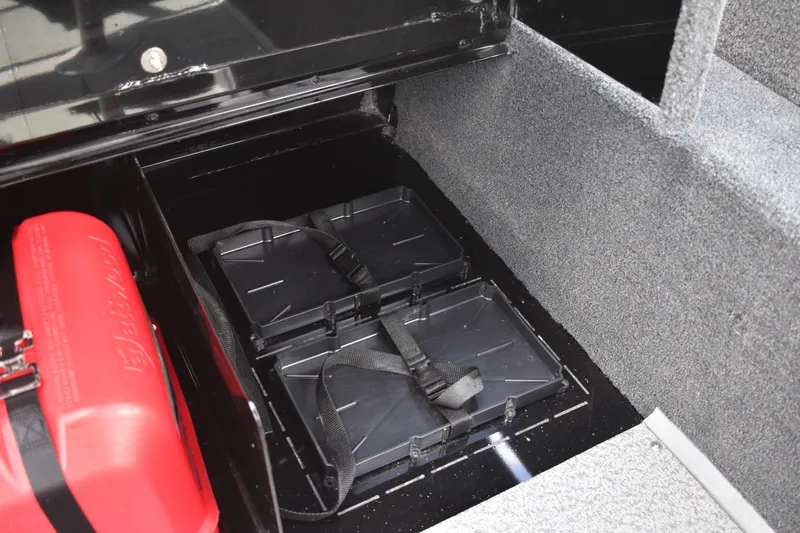 Slide: The Image of 2026 Lowe Fishing Machine 1625WT battery compartment with red fuel tank and secure straps. - 29