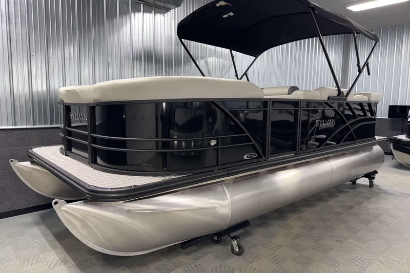 Slide: The Image of 2026 Sylvan Mirage 8520 Cruise pontoon boat in showroom, featuring sleek black design. - 18