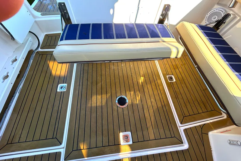Slide: The Image of 2020 Ranger Tugs R-27 boat deck with teak flooring and blue-striped seating. - 19