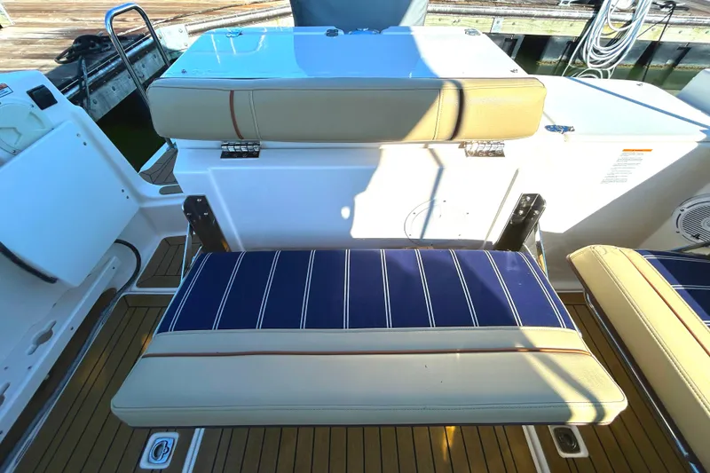 Slide: The Image of 2020 Ranger Tugs R-27 boat seating with blue striped cushions and teak flooring. - 20