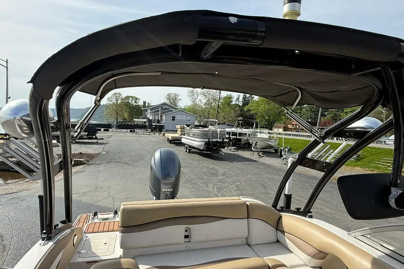 Slide: The Image of 2014 Starcraft Crossover 210 SCX OB boat with canopy, parked near a marina. - 12