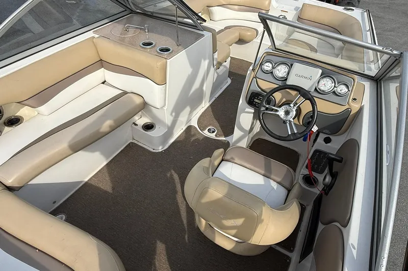 Slide: The Image of 2014 Starcraft Crossover 210 SCX OB boat interior with beige seating and steering console. - 8