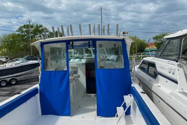 Slide: The Image of 2007 Baha Cruisers 251 GLE boat with blue canopy, docked alongside other boats. - 7