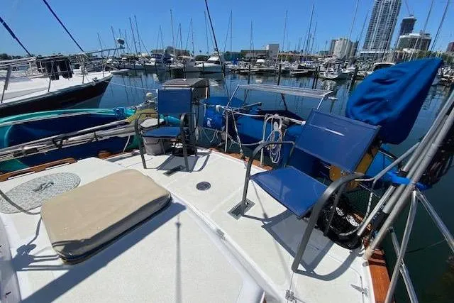 Slide: The Image of Sailboat deck view of 1982 Endeavour 40 at marina, featuring blue chairs and clear skies. - 17