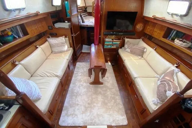 Slide: The Image of Cozy 1982 Endeavour 40 yacht interior with beige seating, wooden accents, and a central table. - 31