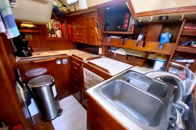 Slide: The Image of Compact kitchen in a 1982 Endeavour 40 sailboat, featuring wooden cabinetry and modern appliances. - 37