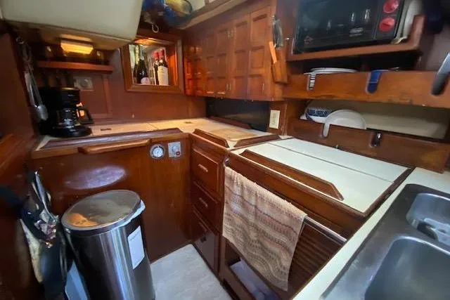 Slide: The Image of 1982 Endeavour 40 yacht kitchen with wooden cabinetry, appliances, and compact layout. - 38