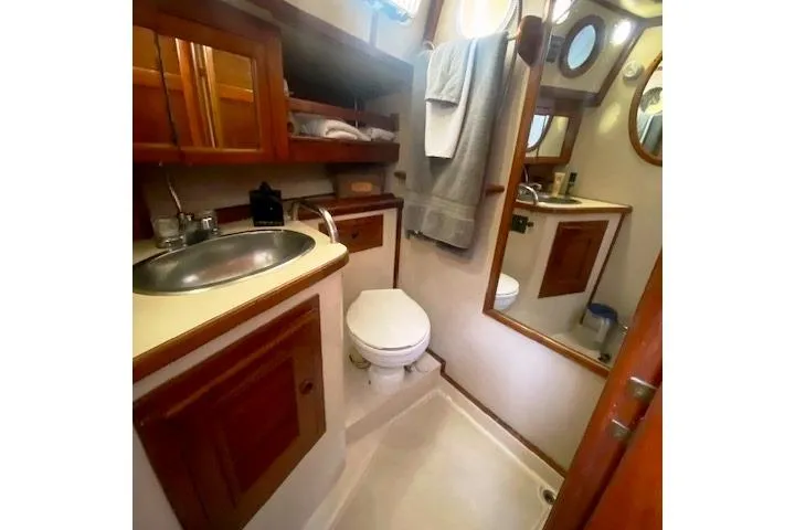 Slide: The Image of 1982 Endeavour 40 yacht bathroom with sink, toilet, mirror, and wooden cabinetry. - 46