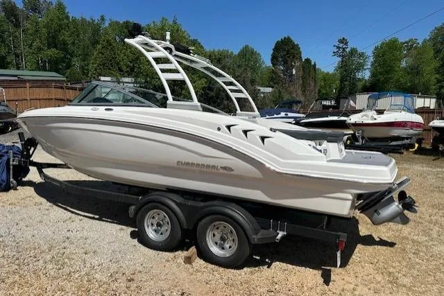 Slide: The Image of 2023 Chaparral 23 SSi boat on trailer, parked outdoors, surrounded by trees and other boats. - 16