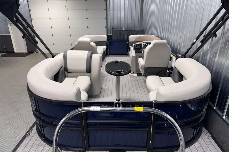 Slide: The Image of 2026 Sylvan Mirage 8520 LZ PTS Tritoon with luxurious seating in a garage setting. - 2