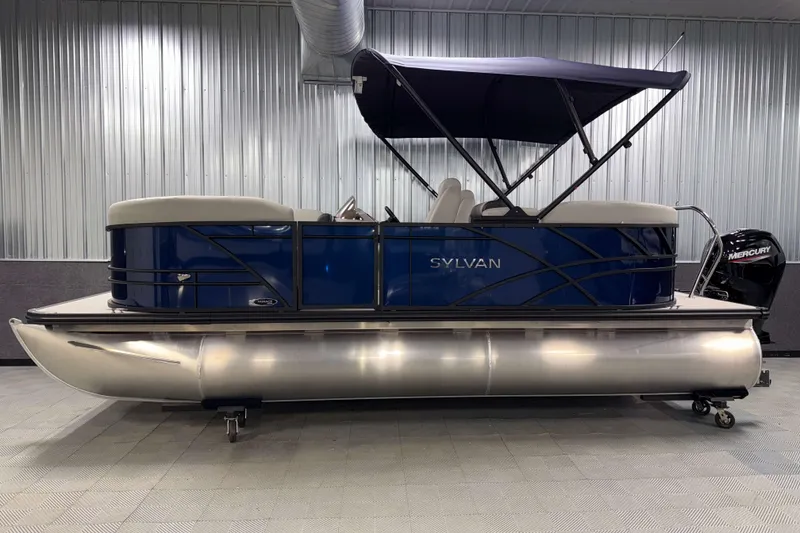 Slide: The Image of 2026 Sylvan Mirage 8520 LZ PTS Tritoon boat with blue exterior and canopy in showroom. - 20
