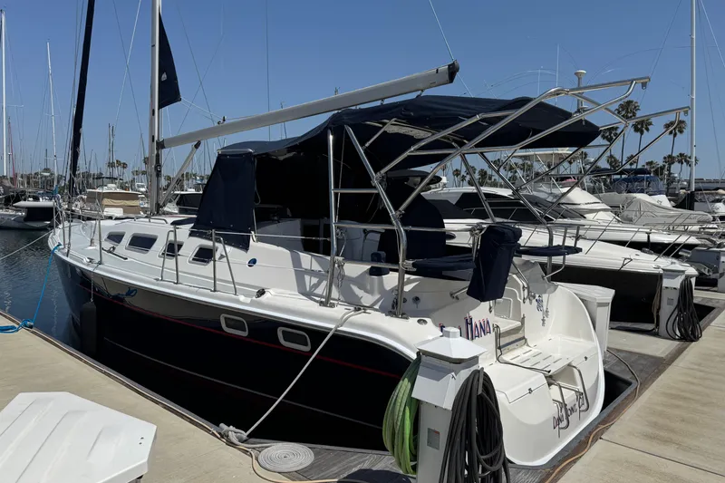 Slide: The Image of 2004 Hunter 41 Aft Cockpit sailboat docked at marina under clear blue sky. - 2