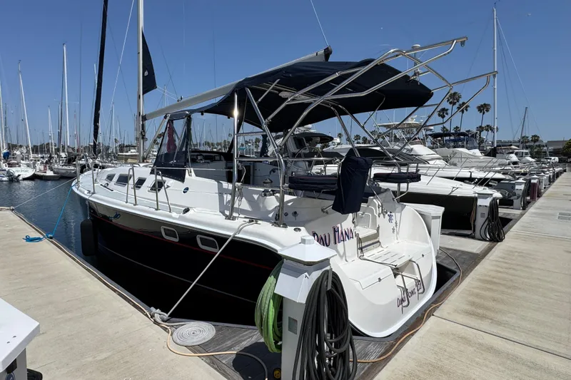 Slide: The Image of 2004 Hunter 41 Aft Cockpit sailboat docked at marina under clear blue sky. - 3