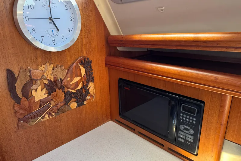 Slide: The Image of Wooden interior of 2004 Hunter 41 Aft Cockpit with clock, microwave, and decorative panel. - 31
