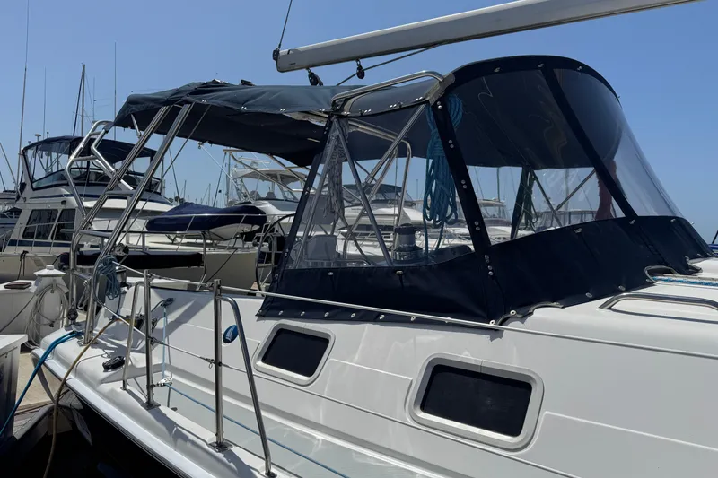 Slide: The Image of 2004 Hunter 41 Aft Cockpit sailboat docked, featuring a sleek design and protective canopy. - 7