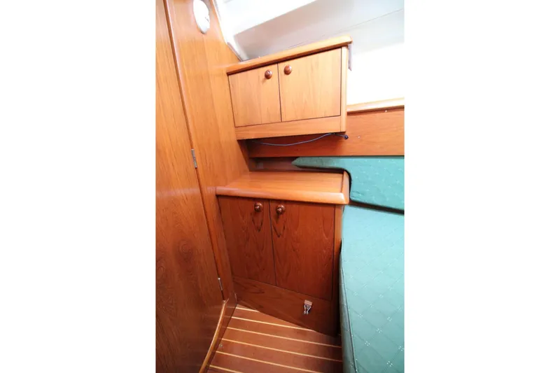 Slide: The Image of Interior cabin of 2004 Jeanneau Sun Odyssey 35, featuring wooden cabinetry and green upholstery. - 23