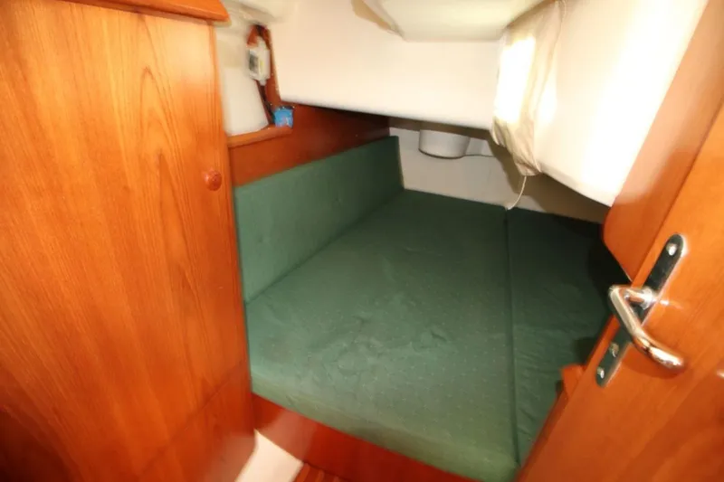 Slide: The Image of 2004 Jeanneau Sun Odyssey 35 cabin interior with green cushioned berth and wooden finish. - 24