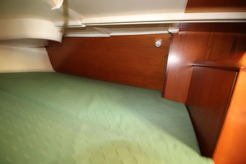 Slide: The Image of Interior cabin of 2004 Jeanneau Sun Odyssey 35 with green bedding and wooden paneling. - 25