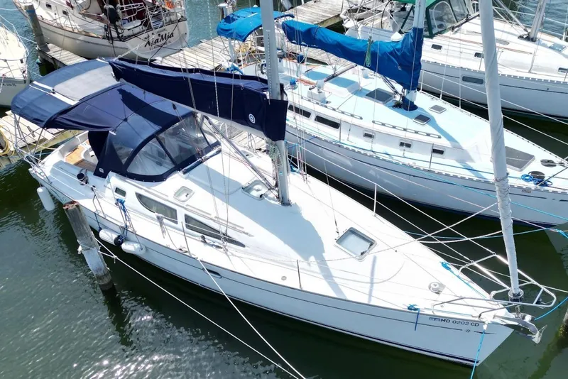 Slide: The Image of 2004 Jeanneau Sun Odyssey 35 sailboat docked at marina, featuring blue canopy and sleek design. - 6