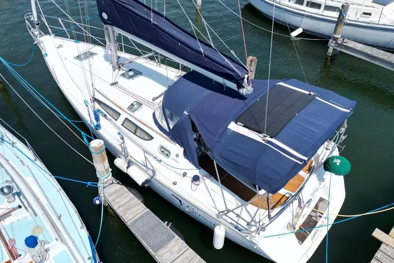 Slide: The Image of 2004 Jeanneau Sun Odyssey 35 sailboat docked, featuring blue canopy and sleek design. - 7