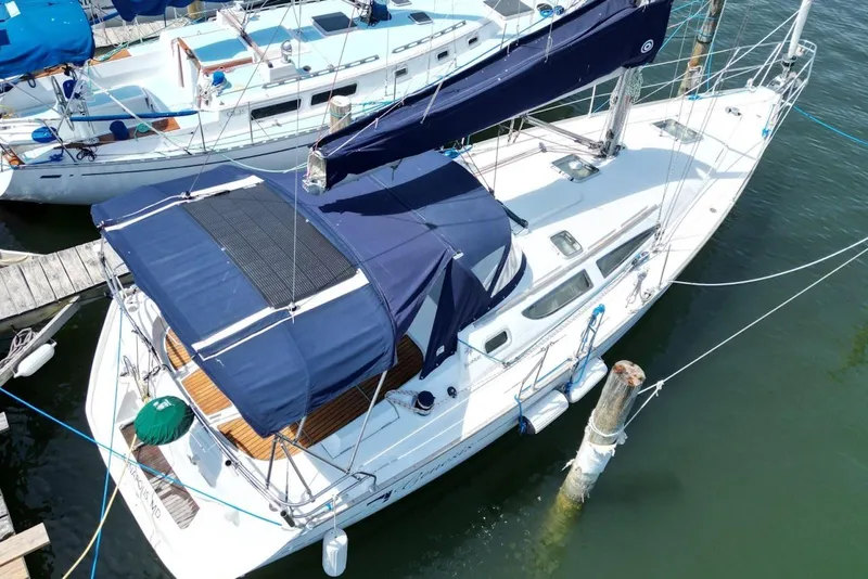 Slide: The Image of 2004 Jeanneau Sun Odyssey 35 sailboat docked at marina, featuring blue canopy and sleek design. - 8