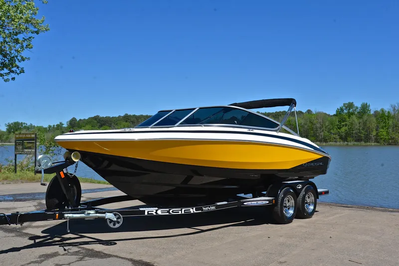 Slide: The Image of 2014 Regal 2100 boat on trailer by a lake, featuring a sleek yellow design. - 10