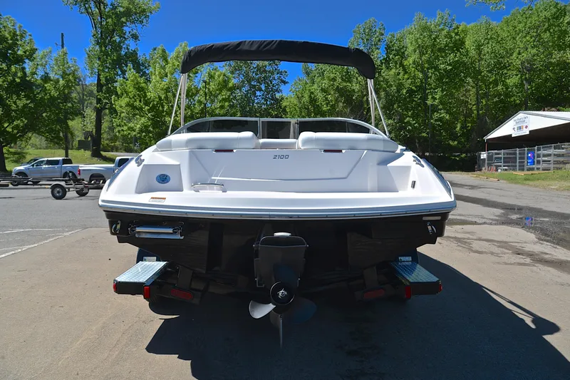 Slide: The Image of 2014 Regal 2100 boat on trailer, parked outdoors with trees in background. - 13