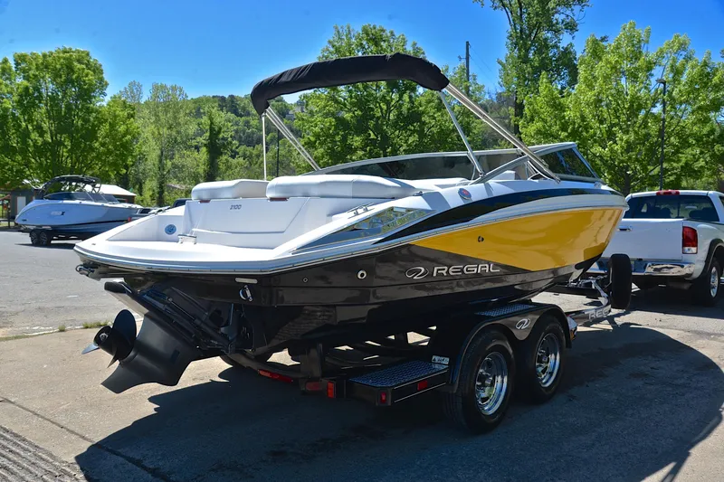 Slide: The Image of 2014 Regal 2100 boat on trailer, yellow and black design, parked outdoors. - 14