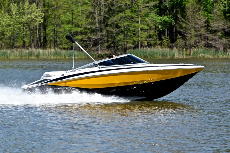 Slide: The Image of 2014 Regal 2100 boat cruising on a lake with lush green trees in the background. - 3