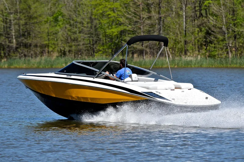 Slide: The Image of 2014 Regal 2100 boat cruising on a lake with lush green trees in the background. - 4