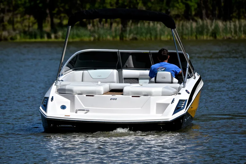 Slide: The Image of 2014 Regal 2100 boat cruising on a calm lake with a person onboard. - 8