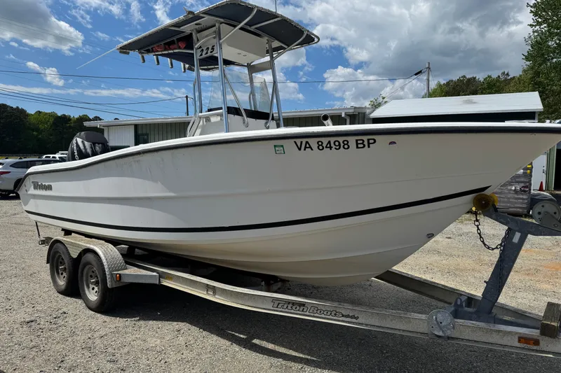 The Image of 2008 Triton 225 CC boat on trailer, parked outdoors under a partly cloudy sky. - 1