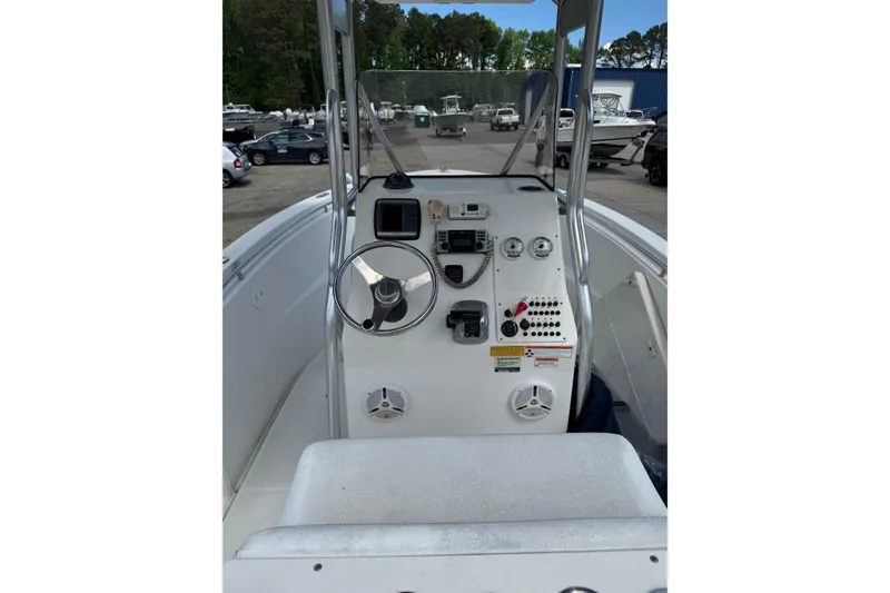 Slide: The Image of 2008 Triton 225 CC boat console with steering wheel and controls in a marina setting. - 4