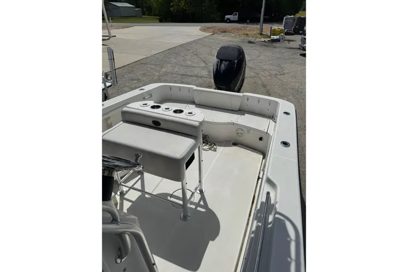 Slide: The Image of 2008 Triton 225 CC boat interior with seating and motor, parked outdoors. - 6