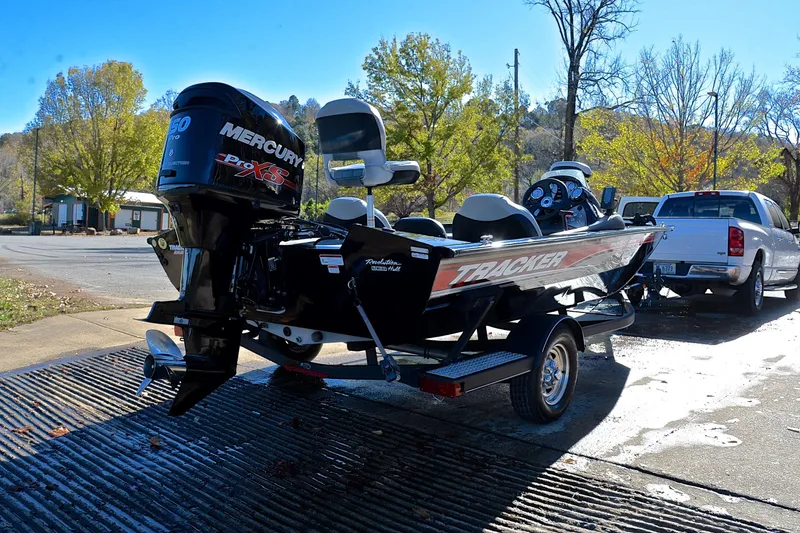 Slide: The Image of 2018 Bass Tracker Pro 19 boat with Mercury engine on trailer, parked near trees. - 14